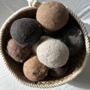 Felted Dryer Balls in a basket on a white surface.