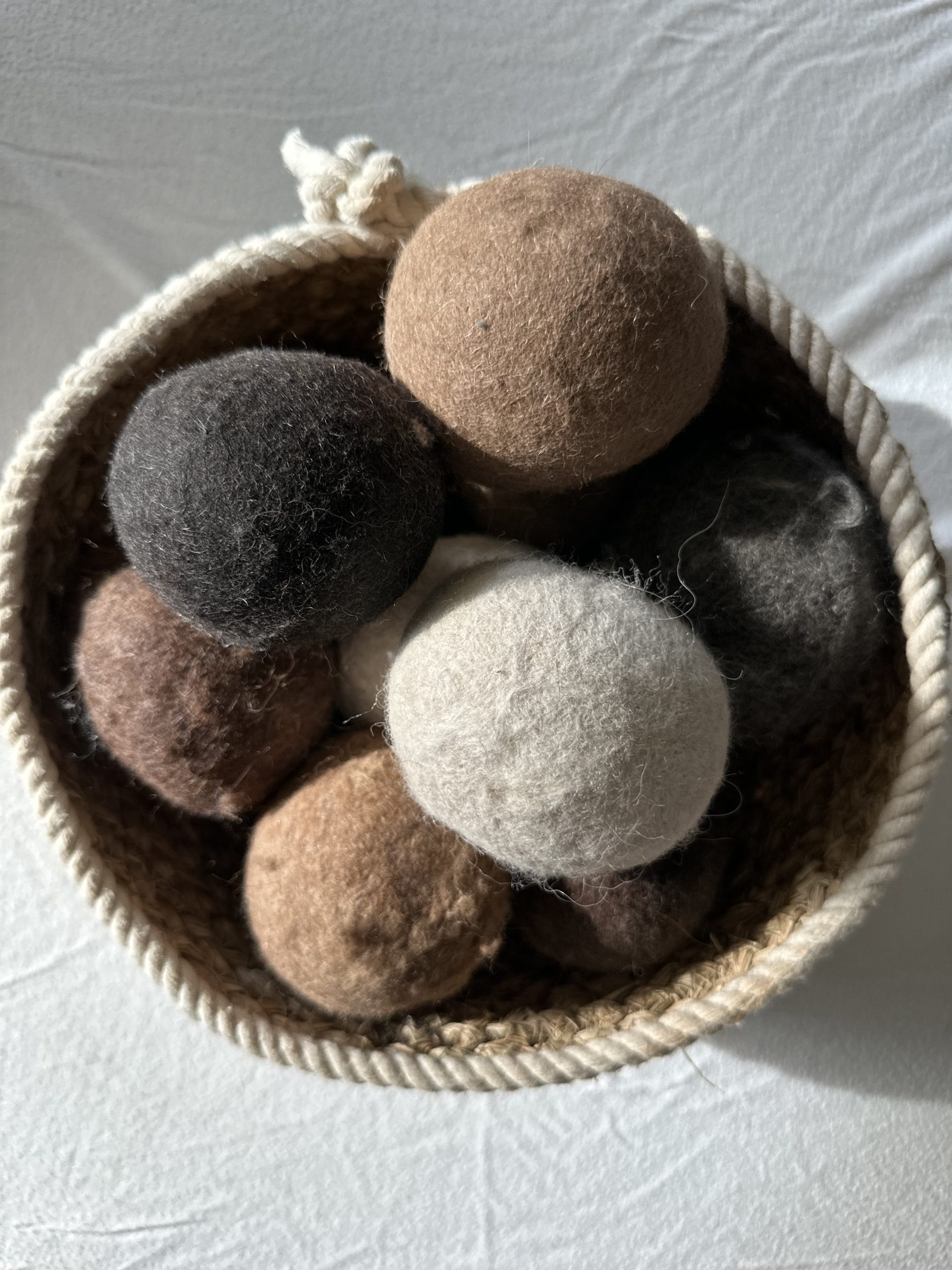 Felted Dryer Balls in a basket on a white surface.