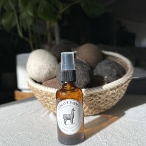 A bottle of Dryer Ball Spray on a table next to a basket.
