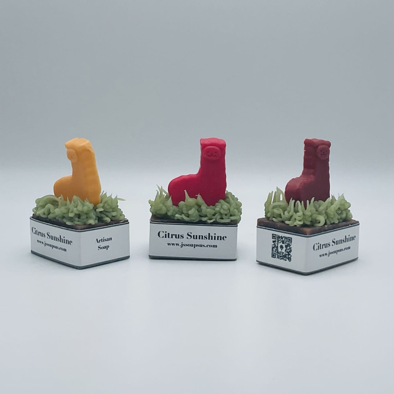 Three locally-sourced Soap figurines sitting on top of grass.