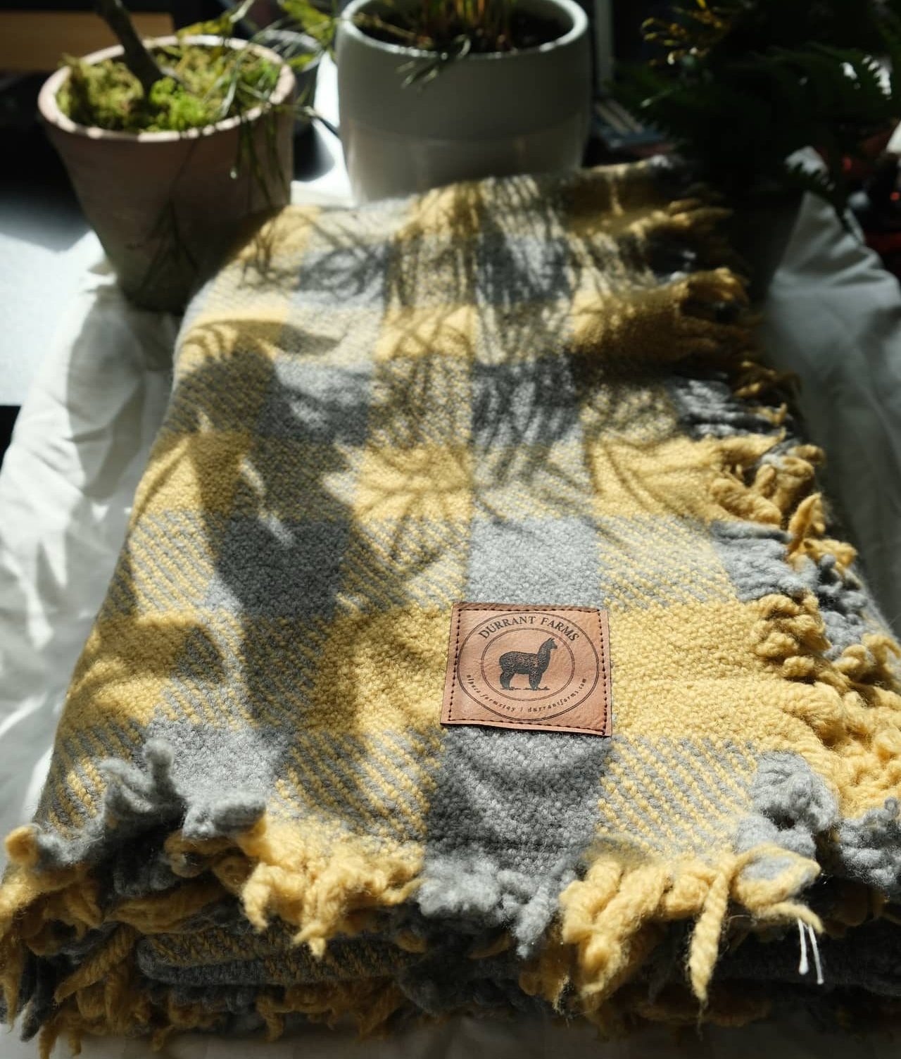 A yellow and grey plaid blanket on a bed.