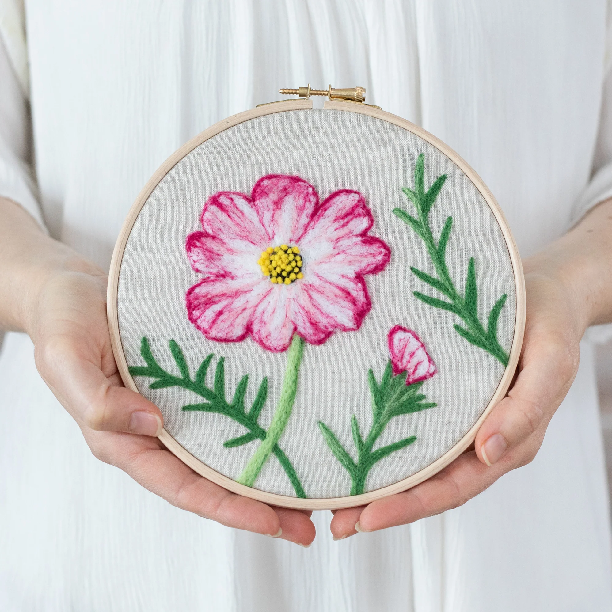 A woman is holding a Cosmos Flower Needle-felting Kit.