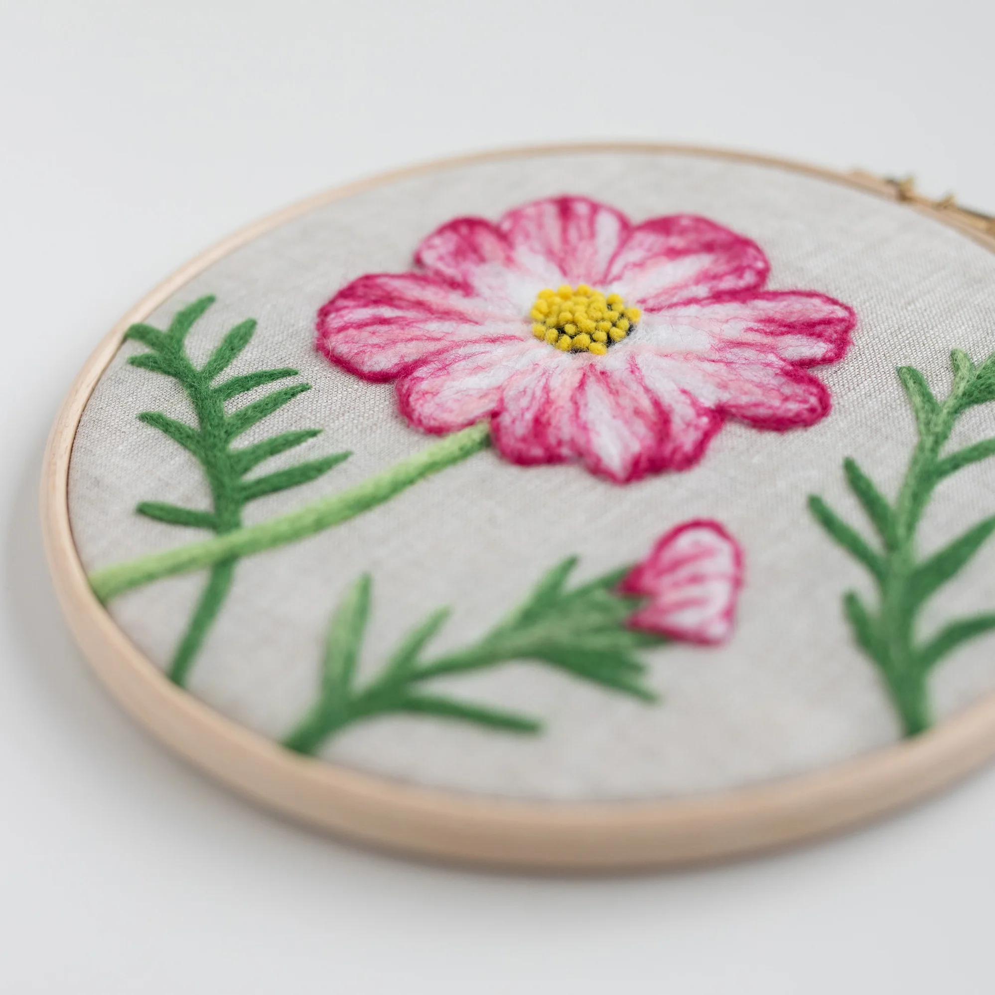 A pink Cosmos Flower Needle-felting Kit is embroidered on a hoop.