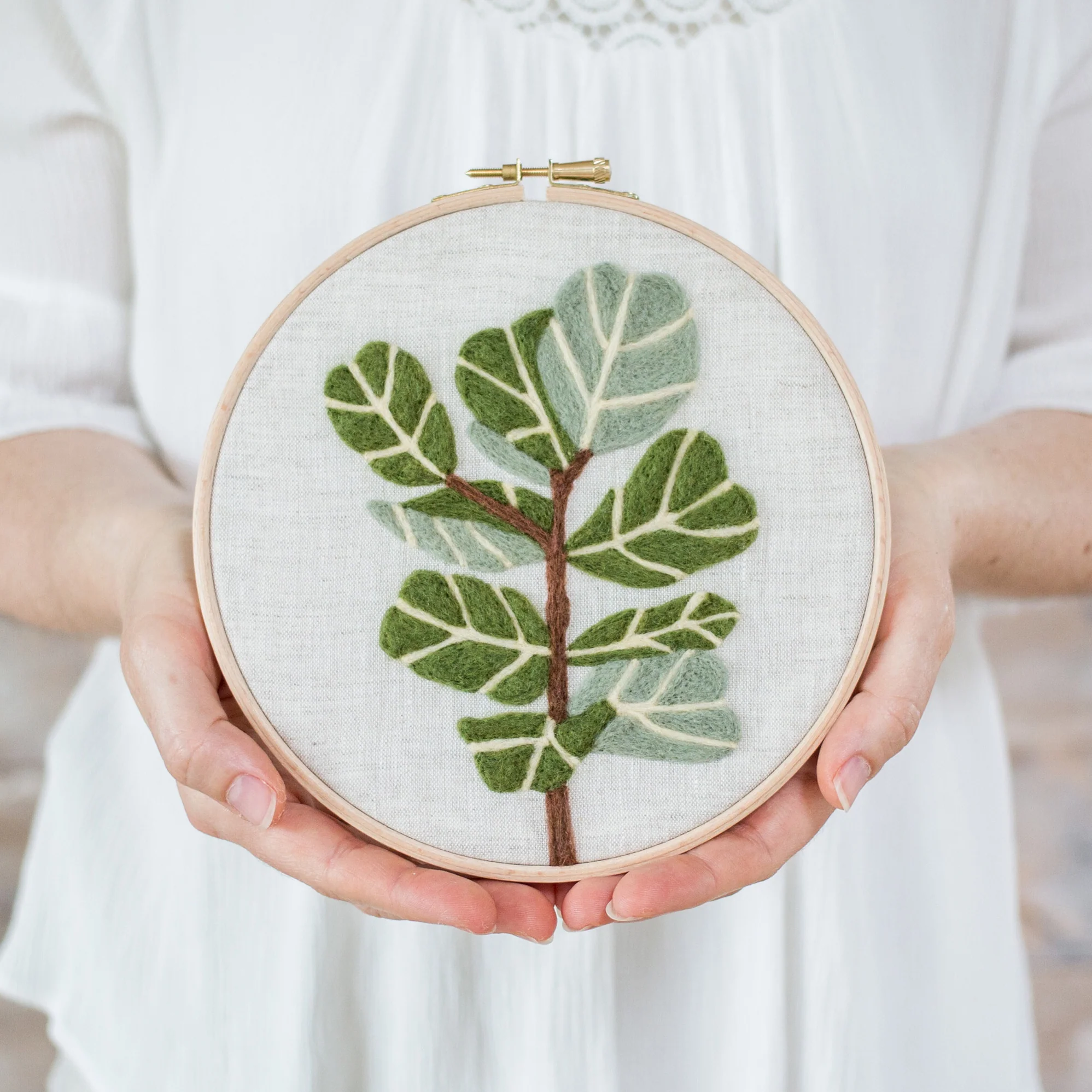 A woman is holding a Fiddle-Leaf Fig Needle Felting Kit.