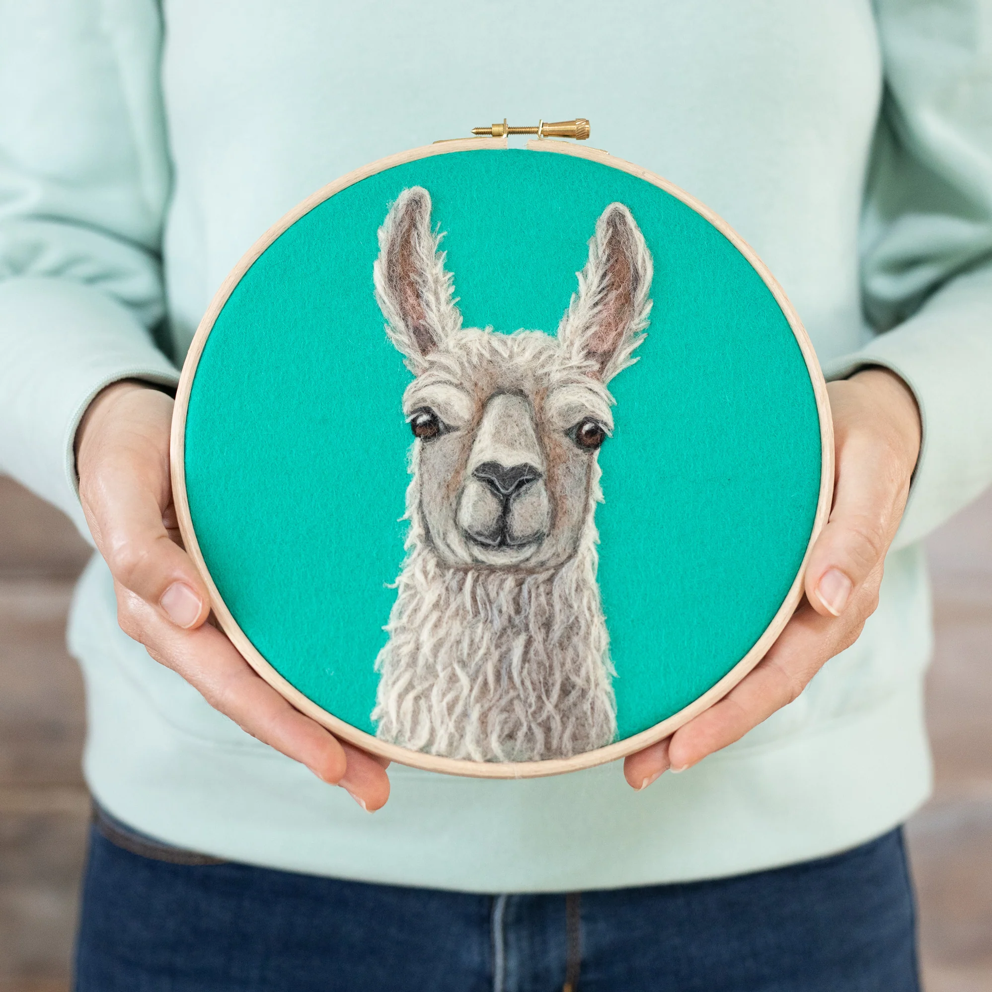 A woman is holding a Llama Needle Felting Kit.