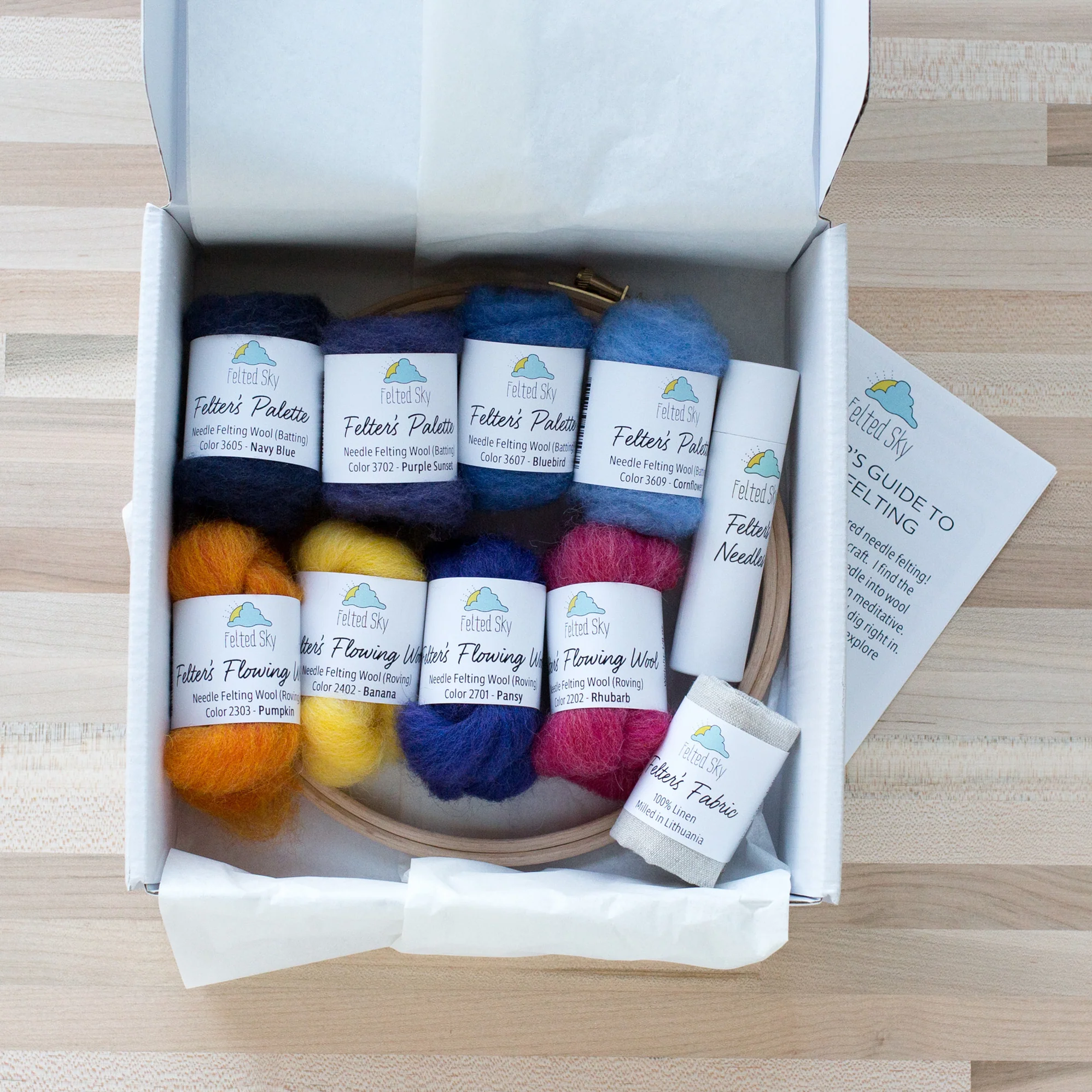 A box filled with different colors of yarn and the Mountain Sunset Needle Felting Kit.